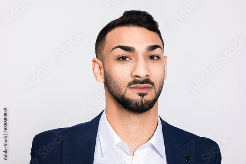 Portrait of serious concentrated in bad mood man looking at camera. Handsome buisnessman successful guy with beard standing over grey background in studio isolated. © ABCreative