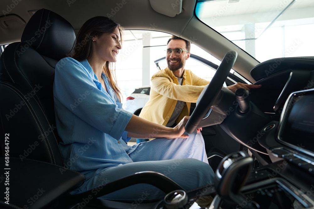 Loving couple looking for auto in car showroom