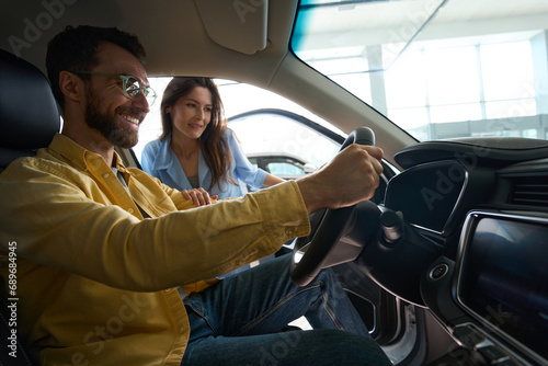 Young couple choosing auto in car showroom