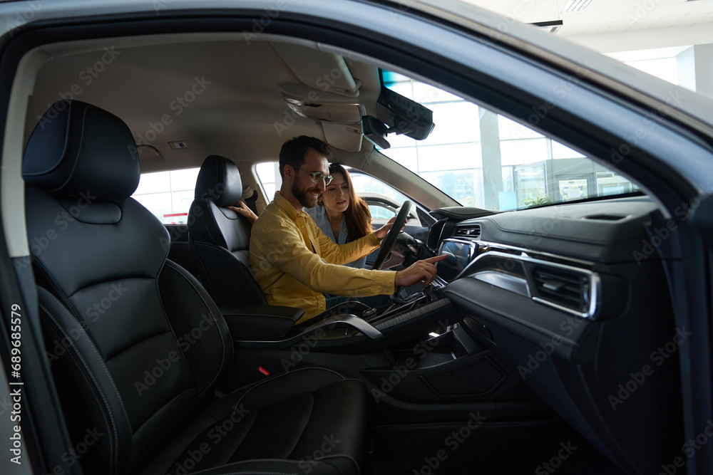 Young couple choosing auto in car showroom