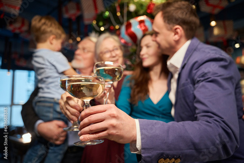 Women and men with boy clinking glasses celebrating Christmas in restaurant