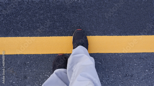 Start Concept.  Man in sneakers standing behind yellow line on asphalt road.