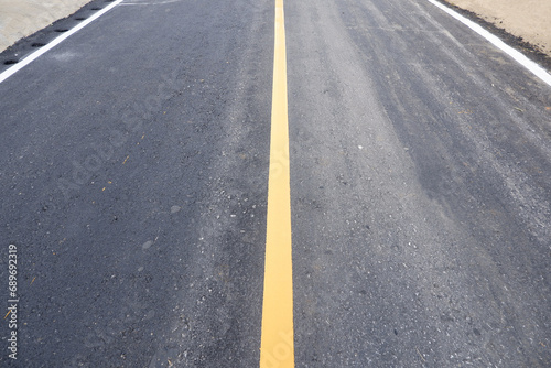 The yellow and white dividing line on the black asphalt road
