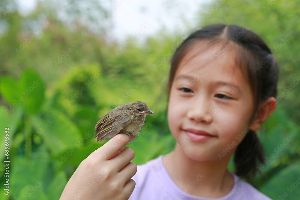 Little sparrow sitting on kid hand, taking care of birds, friendship. Concept of nature of life. Focus at small bird.