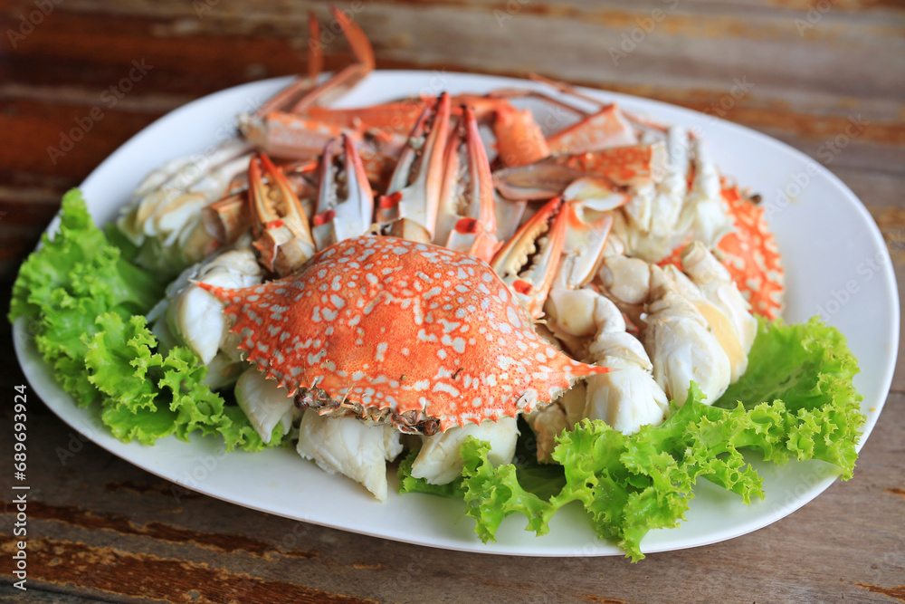 Steamed blue crab or horse crab on white plat against wood background. Top view. Steamed blue crab or horse crab on white plat against wood background. Top view.