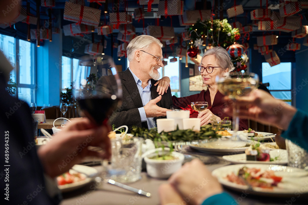 Joyful man and woman sitting at festive table enjoying Christmas dinner