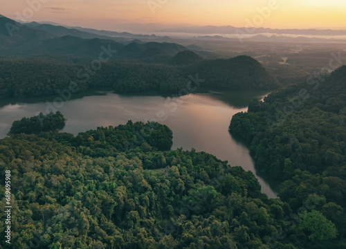Beautiful landscape of green mountains and lake in the morning with sunrise sky. Nature landscape. Watershed forest. Water and forest sustainability concept. Aerial view of mountain with green trees. © Artinun