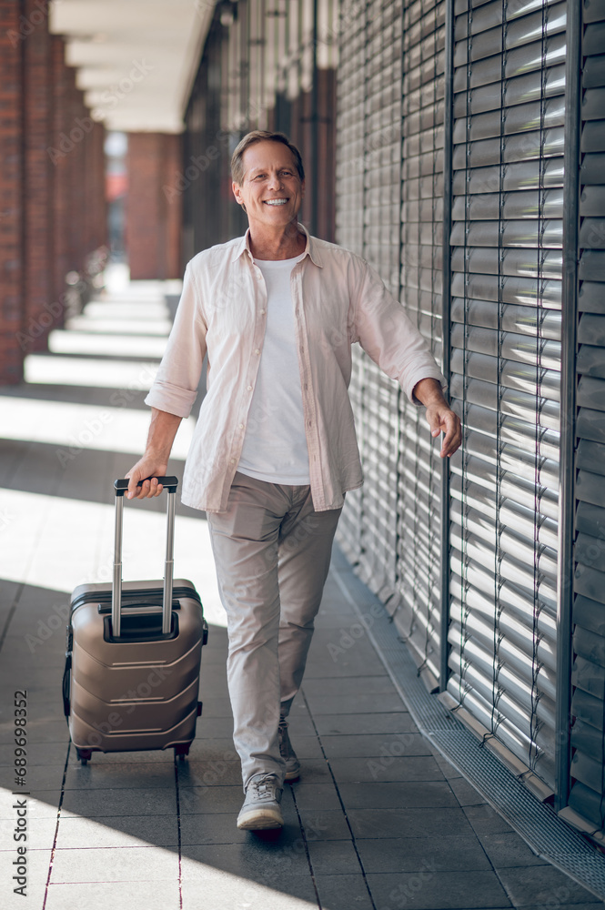 Smiling man with suitcase walking in the city street. Smiling man with suitcase walking in the city street.