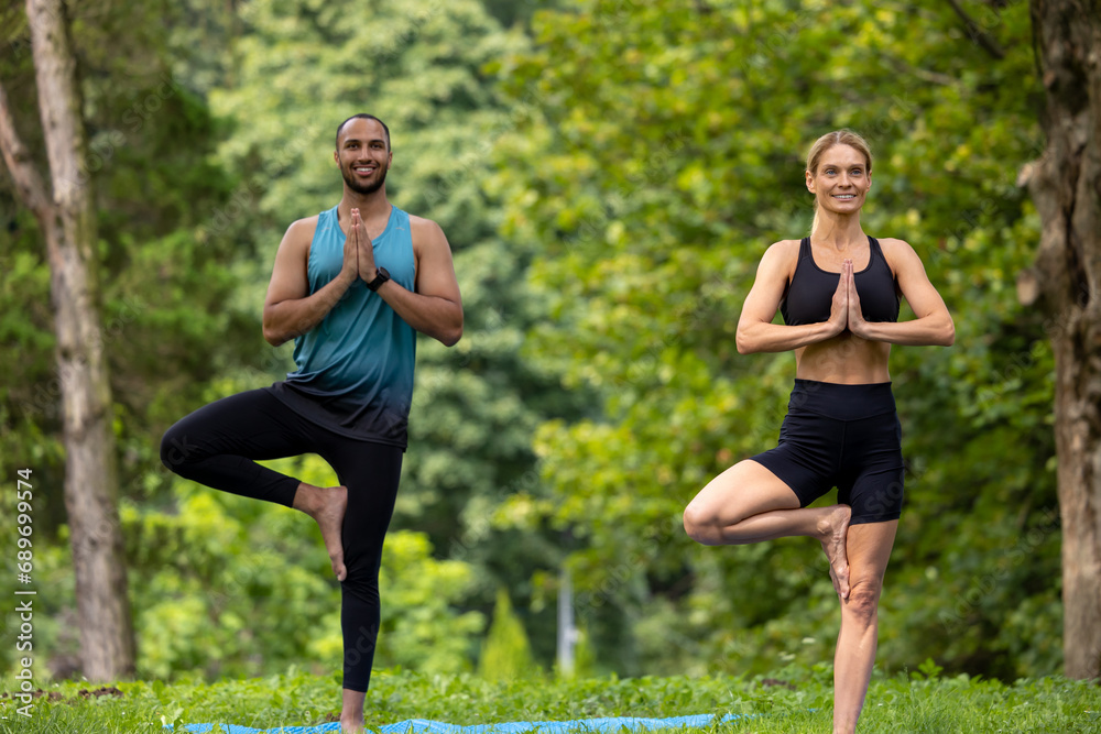 Man and woman doing yoga exercises in green park. Man and woman doing yoga exercises in green park.