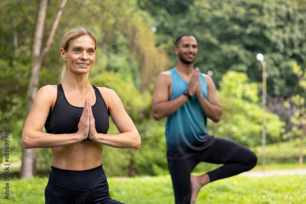 Man and woman doing yoga exercises in green park. Man and woman doing yoga exercises in green park.