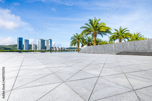 Empty square floor and skyline with green palm trees under blue sky