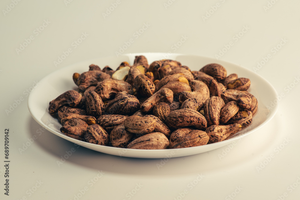 Close up of roasted cashew nuts with skin on white background Close up of roasted cashew nuts with skin on white background