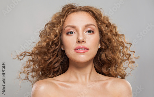 Beautiful redhead woman fashion model with shiny curly brown hair and natural healthy fresh skin on white background. Cosmetology, haircare and beauty treatment concept