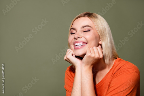 Photo portrait of lovely young lady fists cheeks admire closed eyes excited wear trendy orange garment isolated on khaki color background