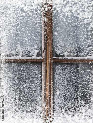 Verschneites altes Holzfenster mit zugefrorener Fensterscheibe