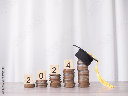 Study goals, Wooden block with number 2024 on stack of coins with graduation hat. The concept of saving money for education, student loan, scholarship, tuition fees in New Year 2024