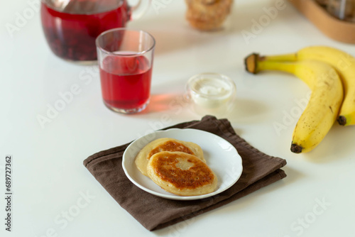 Pancakes on a white plate with banana and berry juice