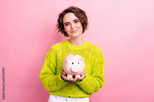 Photo of young girl collect in pig bank earn coins for future studying in european expensive university isolated on pink color background photo