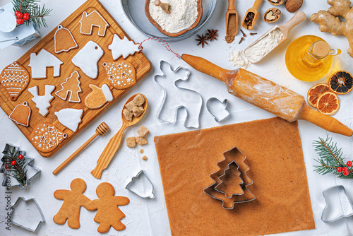 Christmas gingerbread different shaped with sugar icing and ingredients for gingerbread on wooden table, top view, flat lay