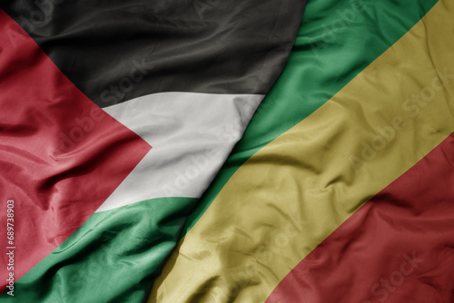 big waving national colorful flag of republic of the congo and national flag of palestine .
