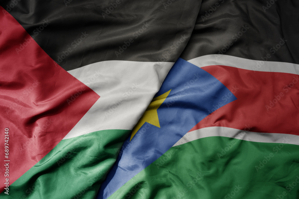 big waving national colorful flag of south sudan and national flag of palestine .