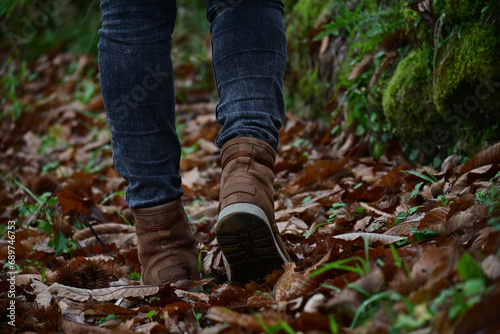 Detail of woman in hiking boots walking in a field in autumn