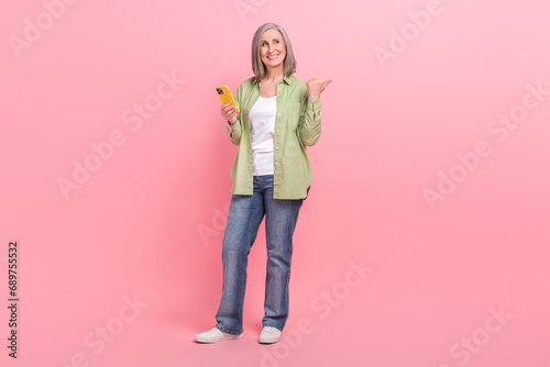 Full length photo of funny cheerful grandmother wear stylish clothes look up empty space offer sale isolated on pink color background