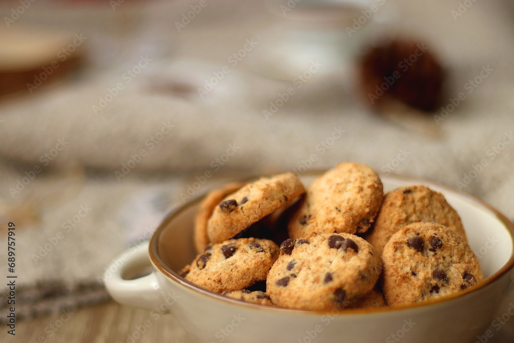 Bowl of cookies, cup of tea, dry oranges, pine cones, books, reading glasses, small presents, various Christmas decorations and lit candles on the table. Cozy Christmas hygge. Selective focus. Bowl of cookies, cup of tea, dry oranges, pine cones, books, reading glasses, small presents, various Christmas decorations and lit candles on the table. Cozy Christmas hygge. Selective focus.