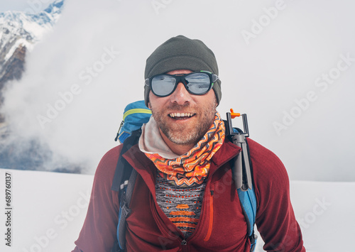 Cheerful laughing climber in sunglasses portrait with backpack ascending Mera peak high slopes at 6000m enjoying beautiful sunny weather, physical challenge in High Himalayas. North-Eastern Nepal. © Soloviova Liudmyla