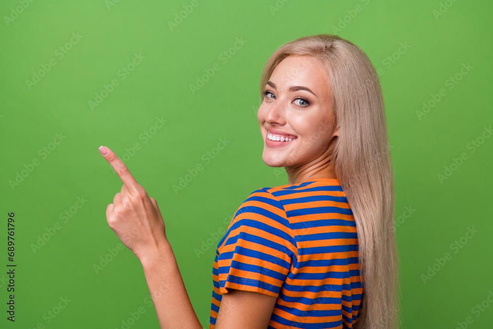 Profile side photo of adorable satisfied girl wear stylish clothes demonstrate empty space billboard isolated on green color background Profile side photo of adorable satisfied girl wear stylish clothes demonstrate empty space billboard isolated on green color background