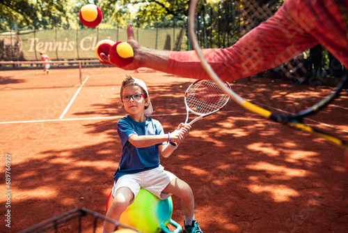 Little boy practicing tennis with coach on clay court photo