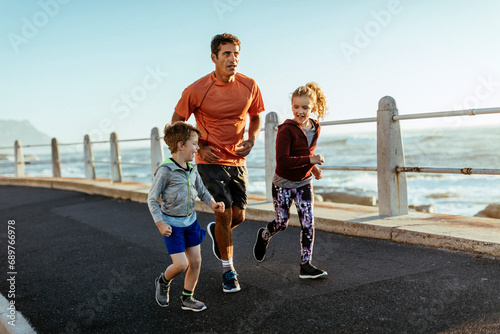 Father running with kids on beach promenade photo