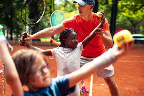 Tennis coach working with little girl on clay court photo