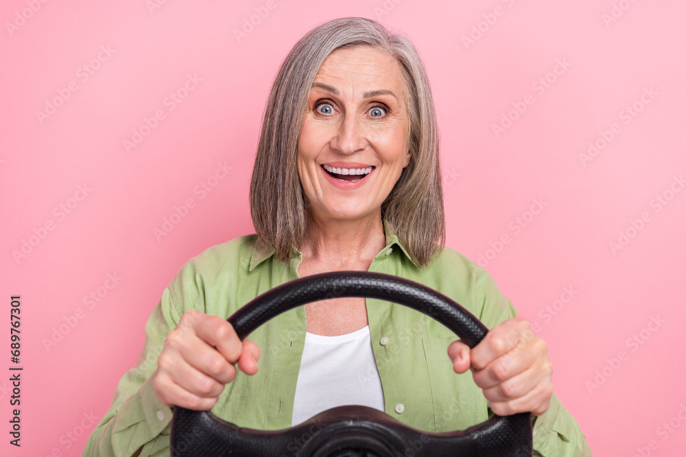 Photo of positive cheerful good mood grandmother wear green stylish clothes drive new own fast car isolated on pink color background Photo of positive cheerful good mood grandmother wear green stylish clothes drive new own fast car isolated on pink color background