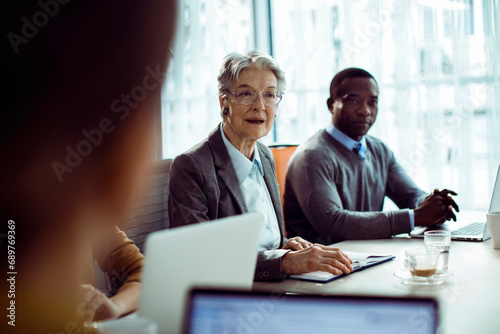 Senior businesswoman leader speaking to colleagues during office meeting photo