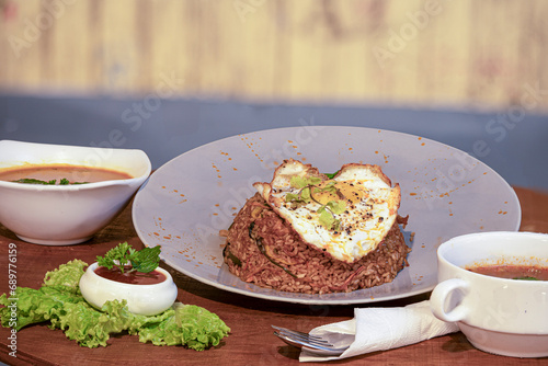 Rice with fried egg and chili sauce on wooden table in restaurant
