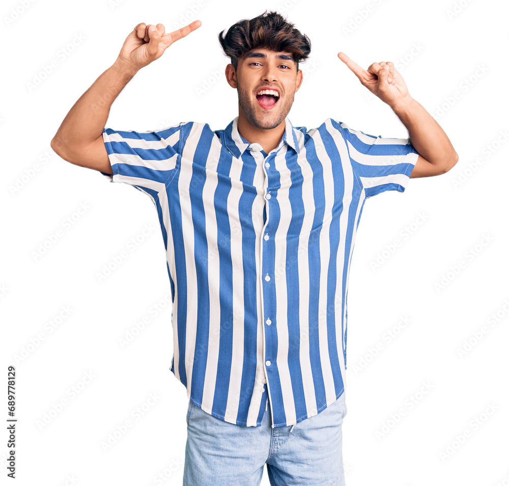 Fototapeta premium Young hispanic man wearing casual clothes smiling amazed and surprised and pointing up with fingers and raised arms.