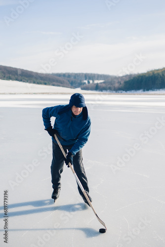 Photography Senior man playing hockey on a frozen lake in winter.