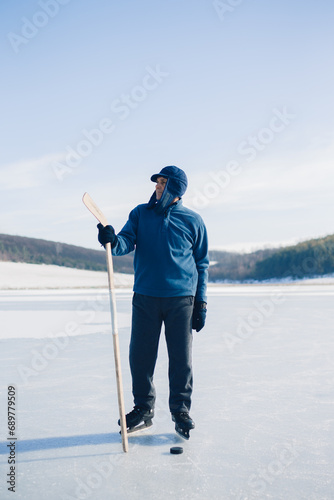 Photography An elderly man practices stricking the puck with hockey stick on a frozen lake in winter