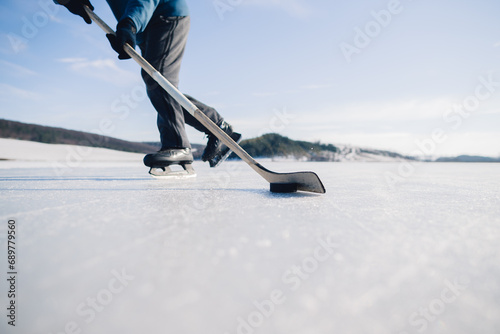 Photography An elderly man practices stricking the puck with hockey stick on a frozen lake in winter
