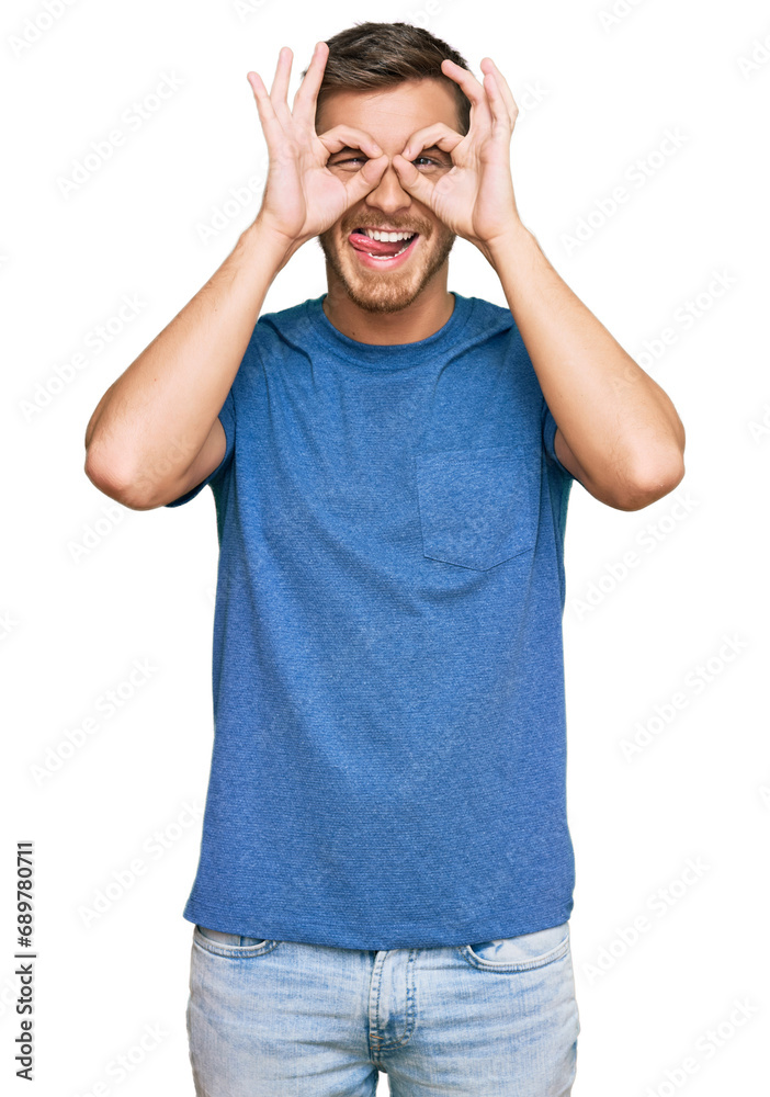Handsome caucasian man wearing casual clothes doing ok gesture like binoculars sticking tongue out, eyes looking through fingers. crazy expression. Handsome caucasian man wearing casual clothes doing ok gesture like binoculars sticking tongue out, eyes looking through fingers. crazy expression.
