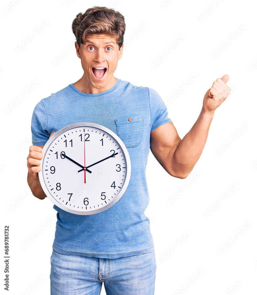 Young handsome man holding big clock screaming proud, celebrating victory and success very excited with raised arms Young handsome man holding big clock screaming proud, celebrating victory and success very excited with raised arms