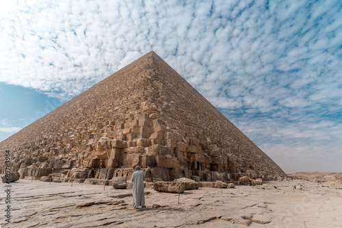 an Egyptian man with gray tunic at the base o Keops' pyramid. El Cairo . Egypt photo