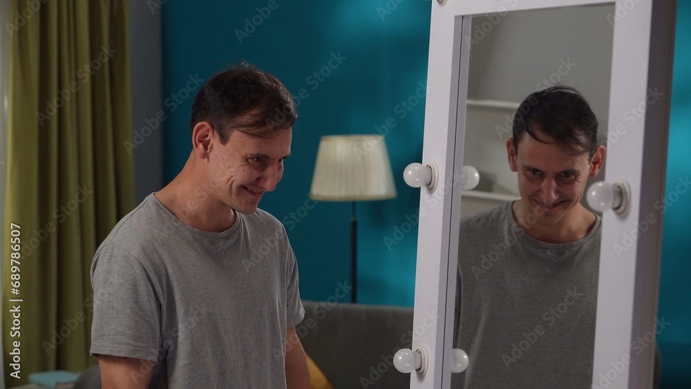 A man with a manic smile looks at his reflection in the mirror close up. Split personality. A man with a manic smile looks at his reflection in the mirror close up. Split personality.