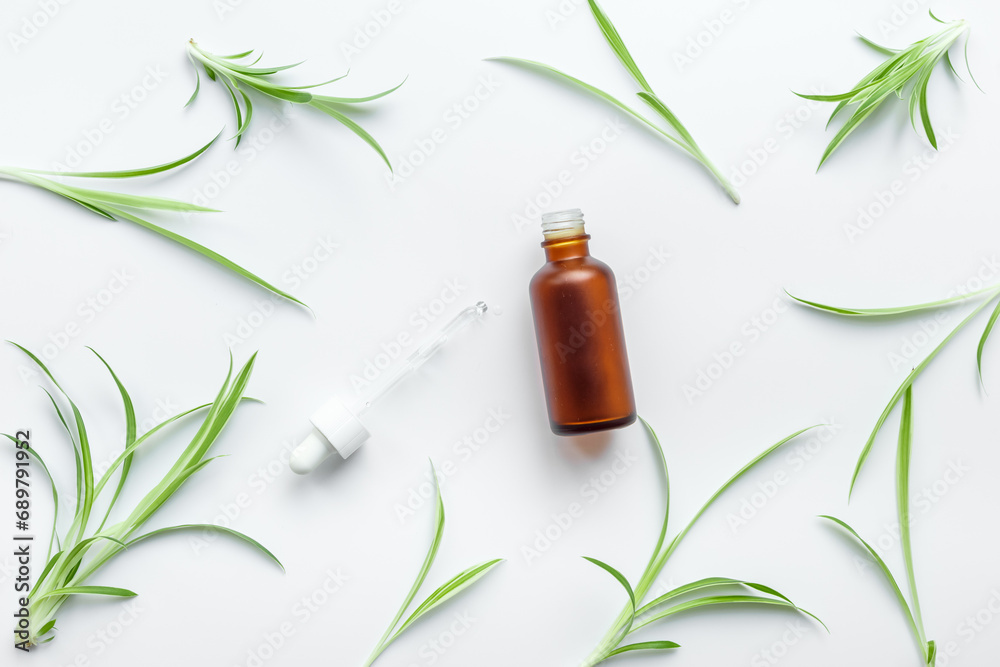 Herbal medicinal cosmetics - essential oil in a bottle with green leaves Herbal medicinal cosmetics - essential oil in a bottle with green leaves
