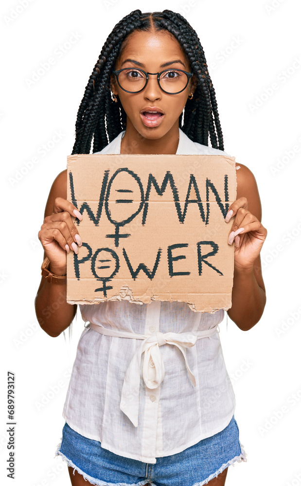 Beautiful hispanic woman holding woman power banner scared and amazed with open mouth for surprise, disbelief face Beautiful hispanic woman holding woman power banner scared and amazed with open mouth for surprise, disbelief face