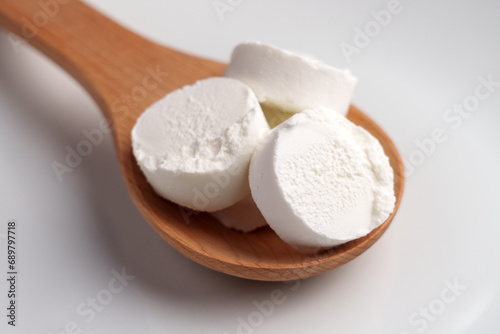 Slices of soft goat cheese in wooden spoon. Traditional dairy product.
