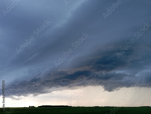 storm clouds over a wheat field, a tornado is visible in the distance.