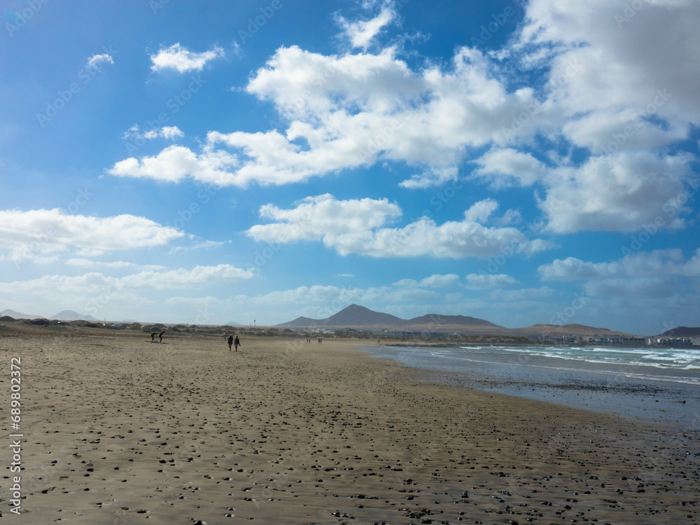 Panoramic view of Famara beach. The popular surfing beach on Lanzarote. In the background the Risco de Famara mountains. Canary Islands, Spain, Europe
