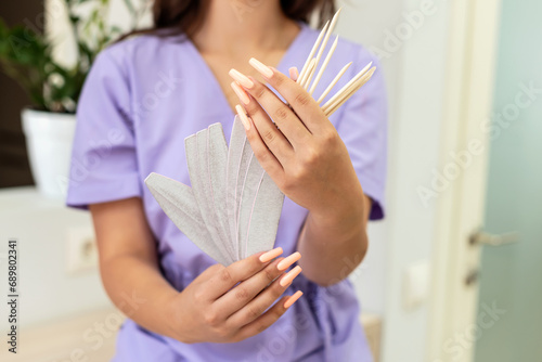Portrait of a manicurist young girl holding nail file for processing nails, wearing purple uniform. Manicure and pedicure master in a beauty salon, training, work break, teenager employee, nail care photo